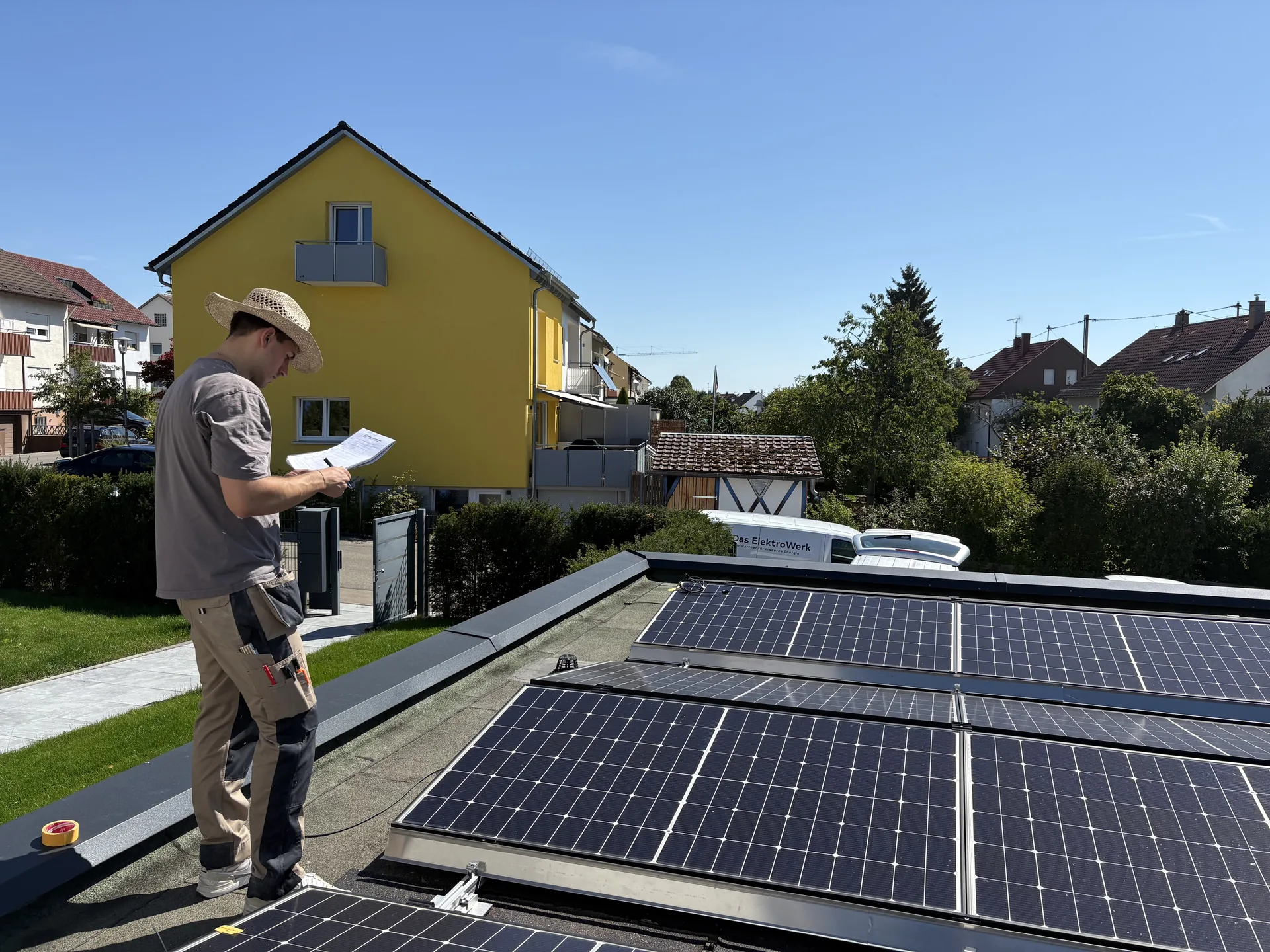Monteur pr&uuml;ft Plan auf PV-Anlage - Das ElektroWerk Stuttgart